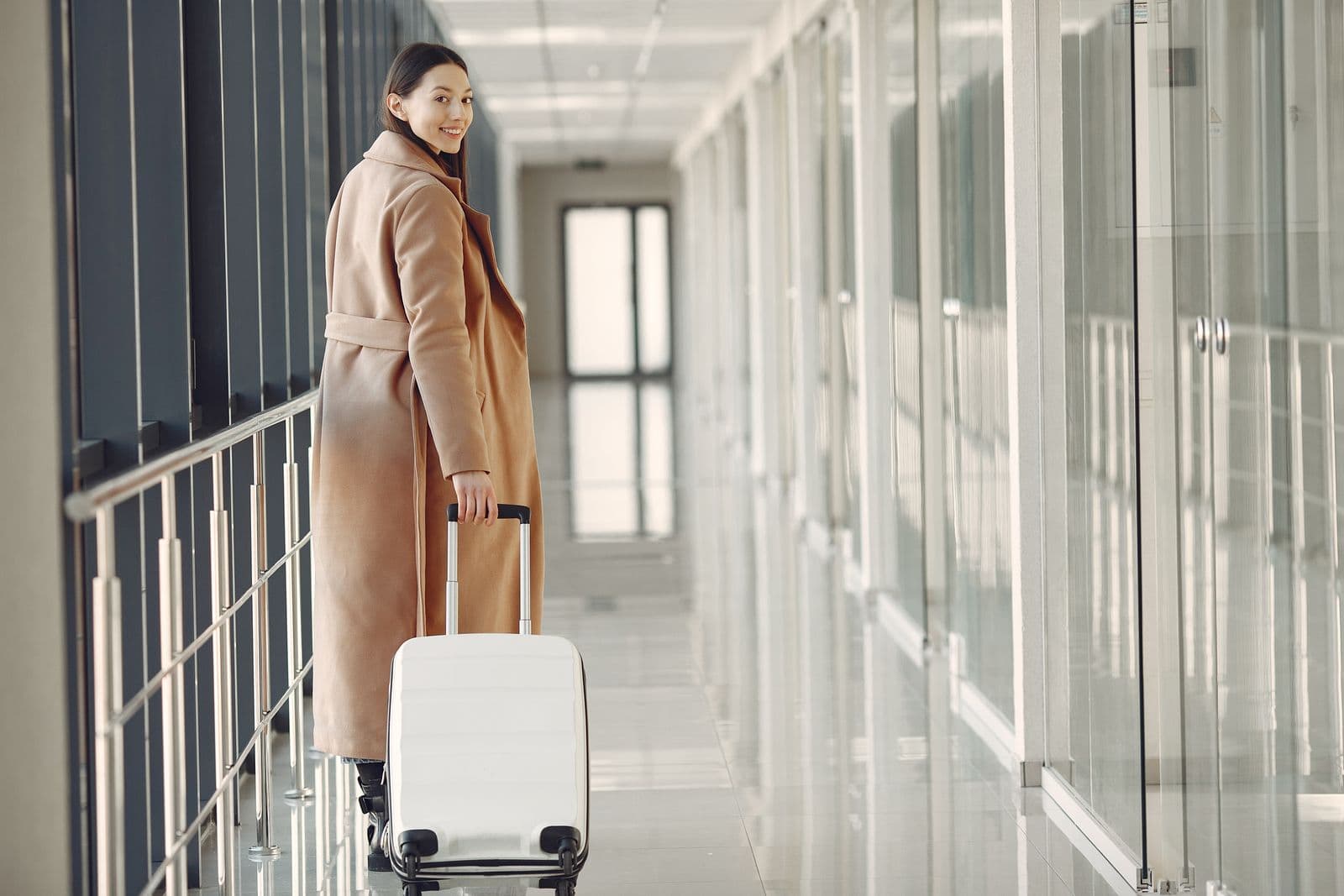 Viajera sonriente con su maleta en el aeropuerto