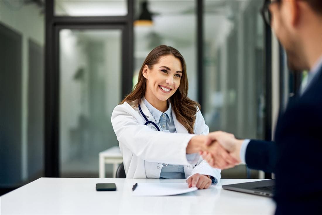 Doctora estrechando la mano de un paciente en su consultorio